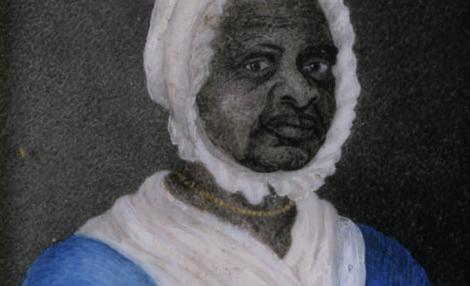 A framed portrait of a Black woman wearing a blue dress with drawstrings at the neck and waist, a white fichu tucked into her dress at the neck, 一顶白帽子, and a gold beaded necklace.